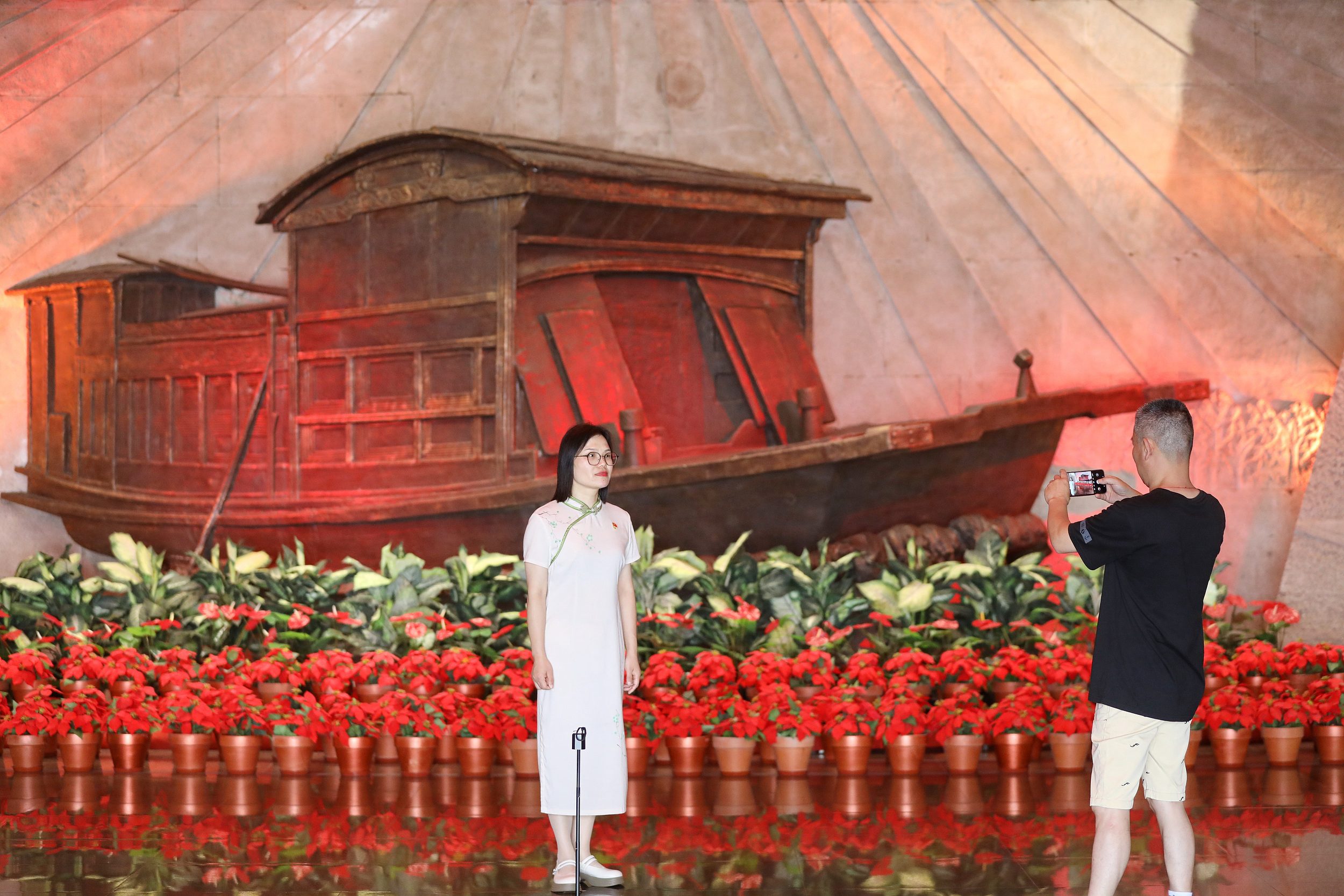 2025年6月24日，浙江嘉興，游客在南湖革命紀(jì)念館與紅船雕塑合影。（圖片來(lái)源：視覺(jué)中國(guó)）