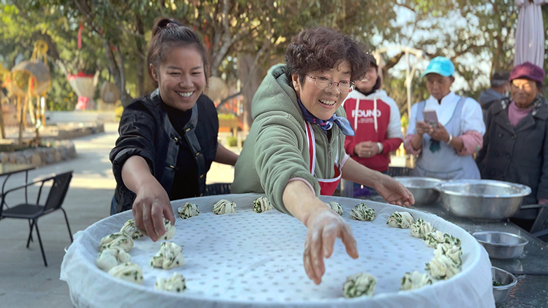【2】旅居者趙發(fā)英（圖左二）教曼海村村民做花卷。陶思源-攝